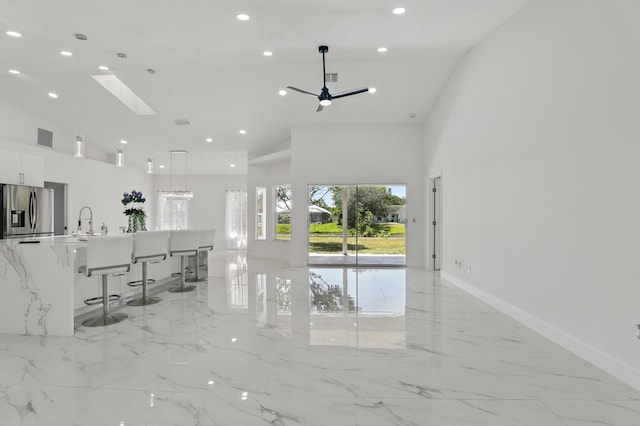 2449 SE Rock Springs Dr, Port Saint Lucie, FL 34952 - living room featuring high vaulted ceiling, light marble finish floors, recessed lighting, a skylight, and baseboards