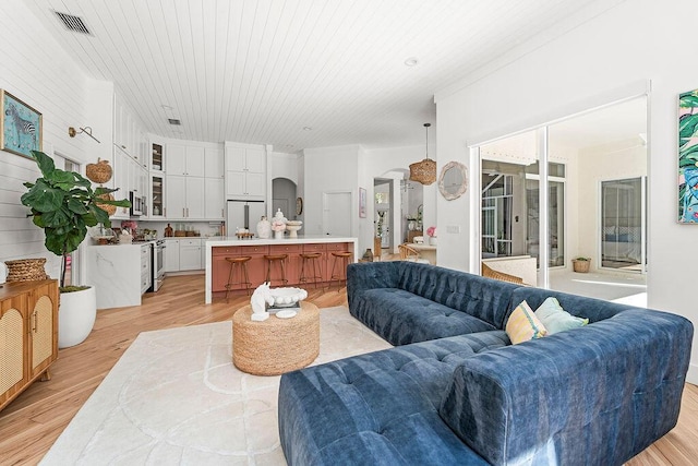 living area with light wood-style floors, arched walkways, visible vents, and wooden ceiling