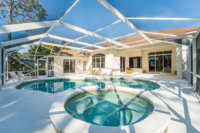 view of swimming pool featuring glass enclosure, a pool with connected hot tub, and a patio area