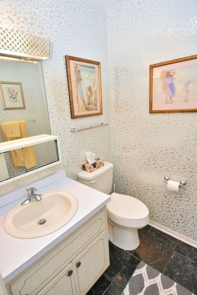 1225 NW 21st St Unit 2010, Stuart, FL 34994 - bathroom featuring vanity, baseboards, wallpapered walls, and toilet