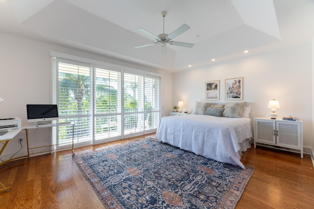 bedroom with a ceiling fan, wood finished floors, access to outside, a tray ceiling, and recessed lighting