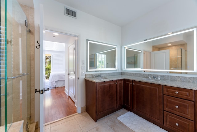 ensuite bathroom with visible vents, a shower stall, and a sink