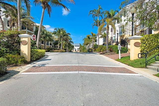 view of road with a residential view, traffic signs, curbs, and street lighting