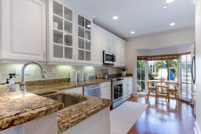 kitchen with white cabinets, stainless steel appliances, a sink, and backsplash