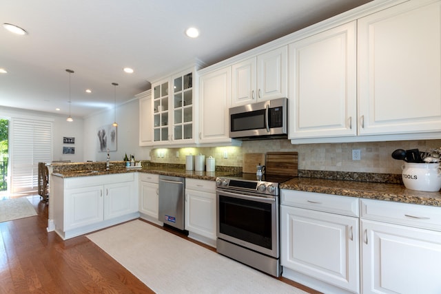 kitchen featuring decorative backsplash, a peninsula, light wood-style floors, white cabinetry, and stainless steel appliances