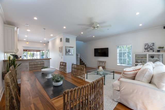living area featuring plenty of natural light, a ceiling fan, stairs, and visible vents