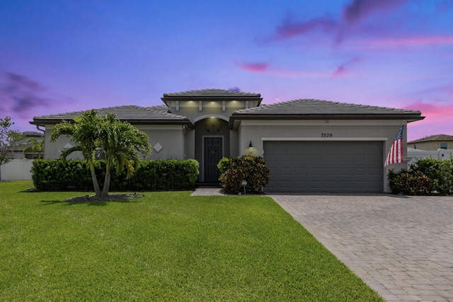 7509 NW Greenspring St, Port Saint Lucie, FL 34987 - view of front of house featuring decorative driveway, an attached garage, a lawn, and stucco siding