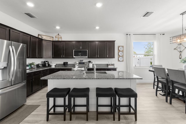 kitchen featuring a sink, appliances with stainless steel finishes, a breakfast bar area, and visible vents