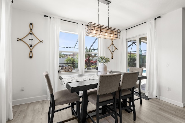 dining area with baseboards, light wood finished floors, and a chandelier