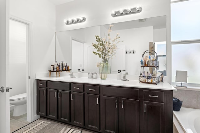 full bathroom with double vanity, a sink, toilet, and a tub to relax in