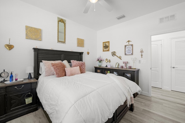 bedroom with a ceiling fan, visible vents, and light wood finished floors