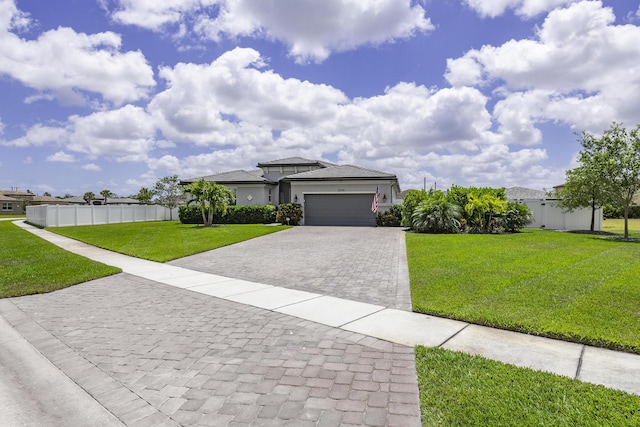 prairie-style house featuring fence, a front lawn, a garage, stucco siding, and decorative driveway
