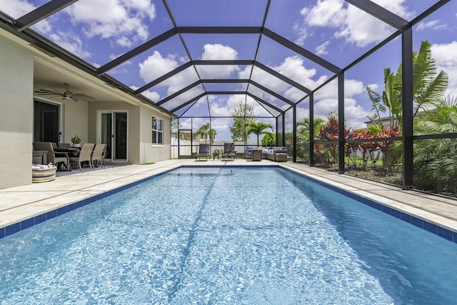 outdoor pool with an outdoor living space, a ceiling fan, glass enclosure, and a patio area