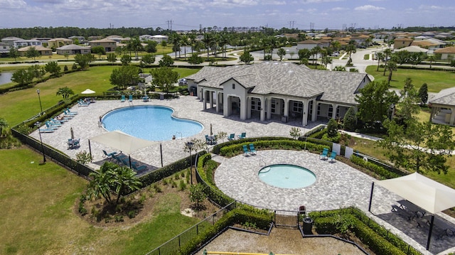 community pool with a lawn, a patio area, fence, and a residential view