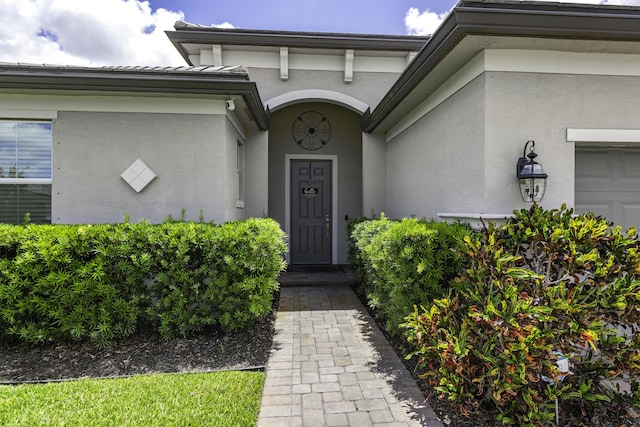 entrance to property with a garage and stucco siding