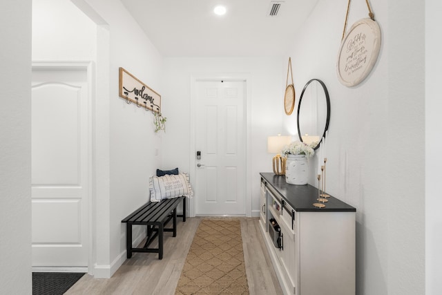 doorway to outside with baseboards, visible vents, and light wood-type flooring