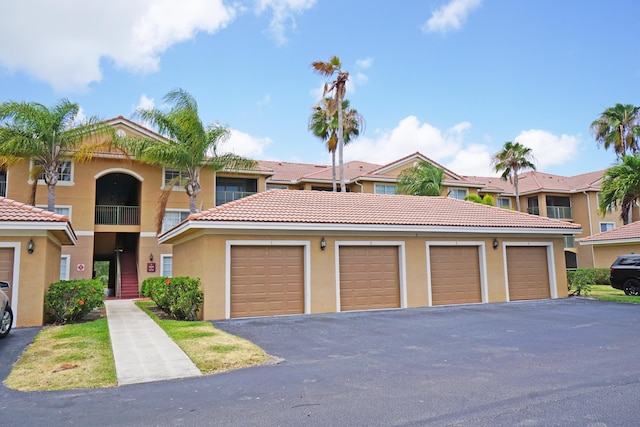 view of front of property featuring stucco siding, a tiled roof, and community garages