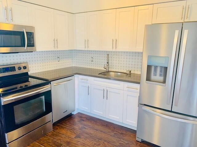 2821 Duke Ln, Delray Beach, FL 33445 - kitchen featuring white cabinets, stainless steel appliances, a sink, and dark wood-style flooring
