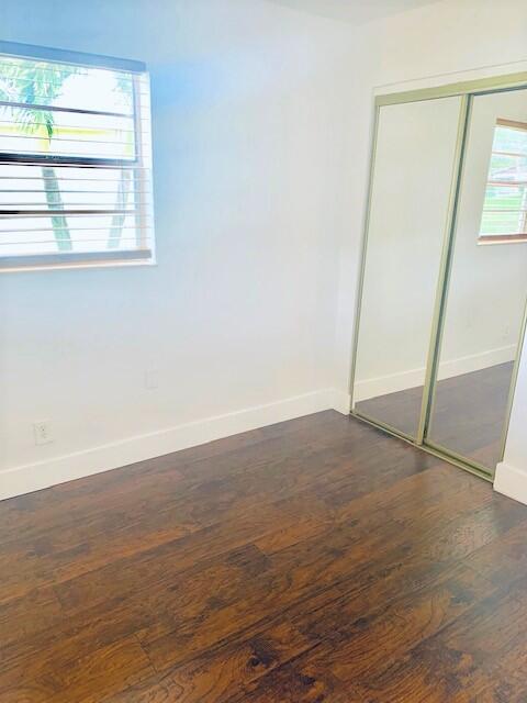 2821 Duke Ln, Delray Beach, FL 33445 - unfurnished bedroom featuring baseboards, dark wood-style floors, and a closet