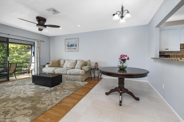 tiled living area featuring a textured ceiling, a ceiling fan, baseboards, recessed lighting, and visible vents