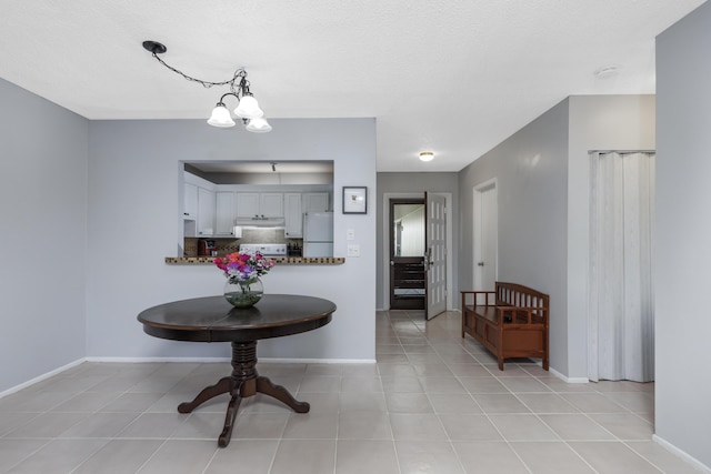 foyer with a textured ceiling, baseboards, a notable chandelier, and light tile patterned floors