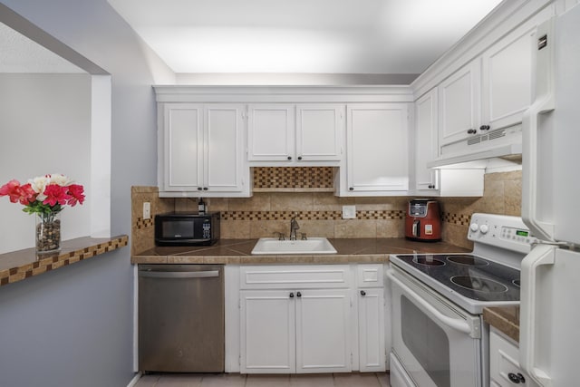 kitchen with decorative backsplash, a sink, white cabinets, under cabinet range hood, and white appliances