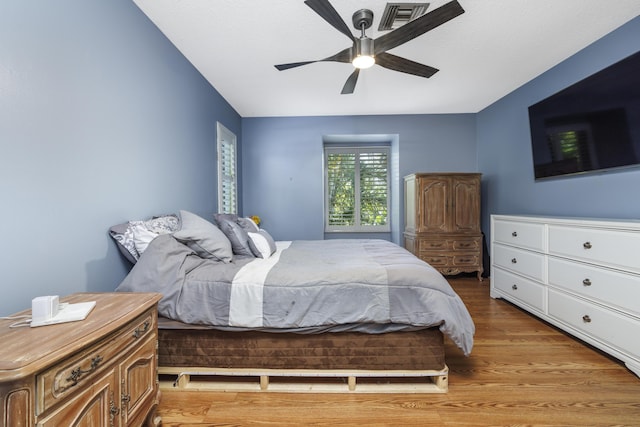 bedroom with a ceiling fan, visible vents, and light wood finished floors