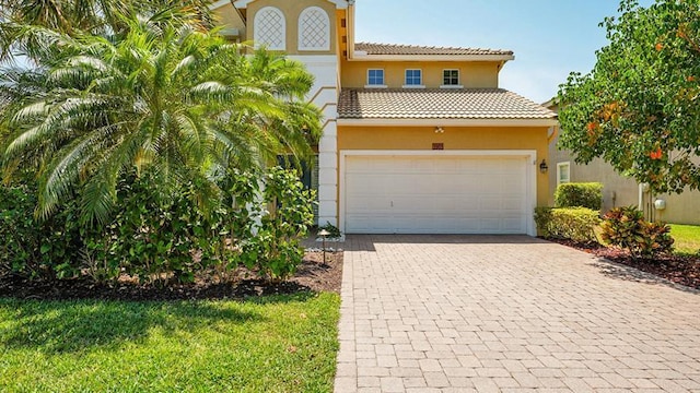 mediterranean / spanish house featuring stucco siding, decorative driveway, a tile roof, and a garage