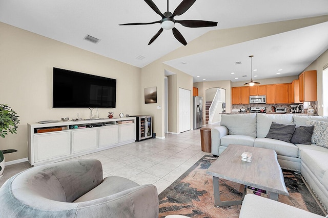 living area with a ceiling fan, lofted ceiling, arched walkways, baseboards, and wine cooler