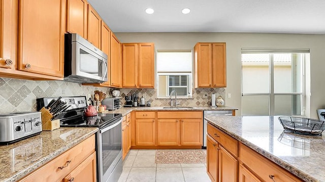 kitchen featuring appliances with stainless steel finishes, a sink, light stone countertops, decorative backsplash, and recessed lighting