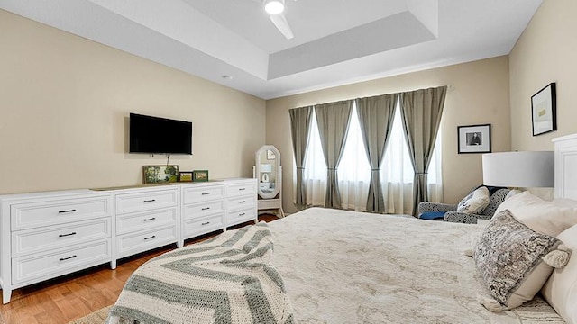 bedroom featuring a tray ceiling and light wood finished floors