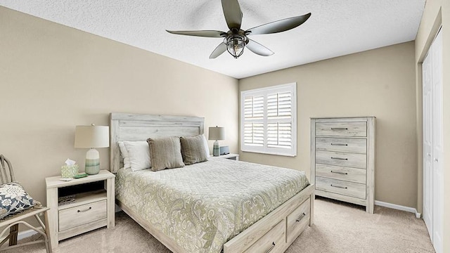 bedroom featuring light colored carpet, baseboards, a ceiling fan, and a textured ceiling