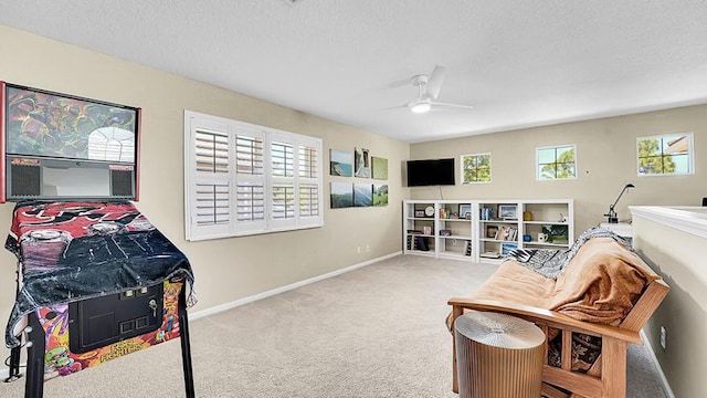 living area with carpet flooring, a ceiling fan, baseboards, and a textured ceiling