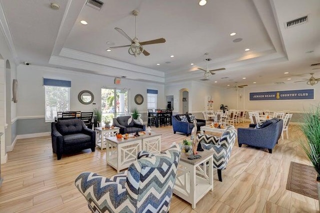 living area with a raised ceiling, a ceiling fan, arched walkways, crown molding, and recessed lighting