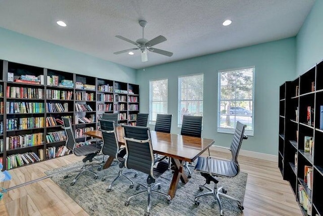 office with wood finished floors, a ceiling fan, a textured ceiling, bookshelves, and baseboards