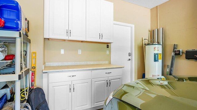 kitchen featuring water heater, light countertops, and white cabinetry