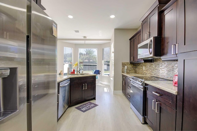 7861 Manor Forest Ln, Boynton Beach, FL 33436 - kitchen with appliances with stainless steel finishes, light wood finished floors, tasteful backsplash, a sink, and baseboards