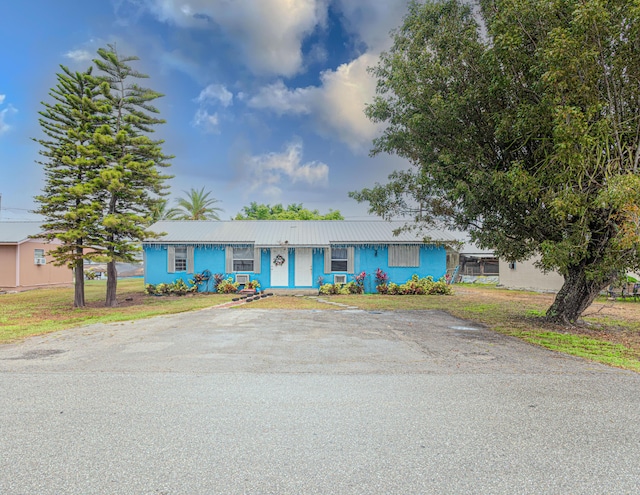 1043 NE 20th St, Belle Glade, FL 33430 - ranch-style home featuring metal roof and a front yard