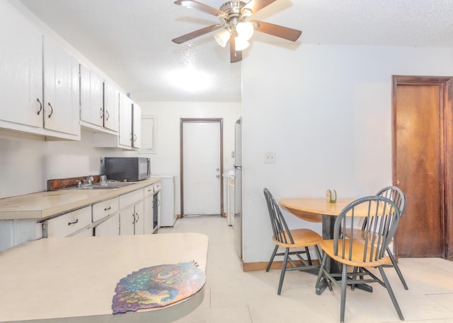 1043 NE 20th St, Belle Glade, FL 33430 - kitchen featuring black microwave, a sink, light countertops, a textured ceiling, and a ceiling fan