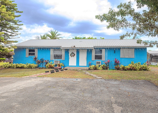 1043 NE 20th St, Belle Glade, FL 33430 - ranch-style house featuring stucco siding, metal roof, and a front lawn