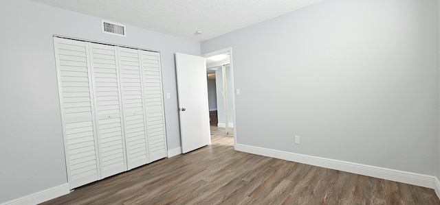 4141 NW 44th Ave Unit 217, Lauderdale Lakes, FL 33319 - unfurnished bedroom featuring a textured ceiling, visible vents, wood finished floors, baseboards, and a closet