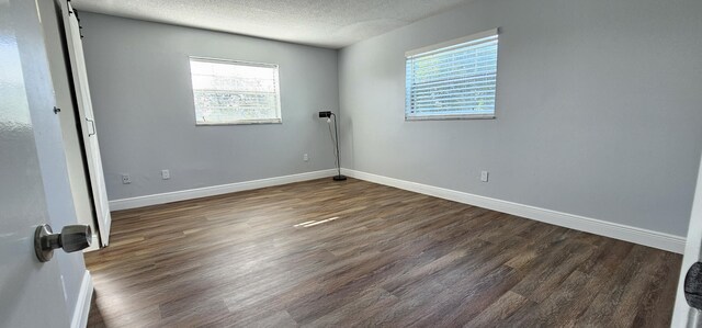 4141 NW 44th Ave Unit 217, Lauderdale Lakes, FL 33319 - unfurnished room featuring baseboards, a textured ceiling, a healthy amount of sunlight, and dark wood-type flooring
