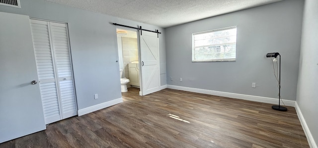 4141 NW 44th Ave Unit 217, Lauderdale Lakes, FL 33319 - unfurnished bedroom with visible vents, a barn door, a textured ceiling, and wood finished floors