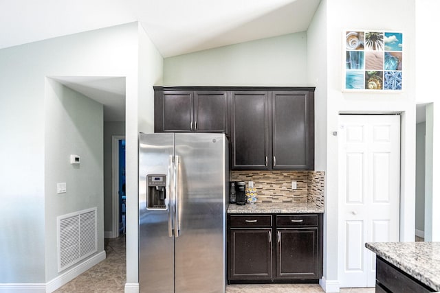 1566 SW Andalusia Rd, Port Saint Lucie, FL 34953 - kitchen with light stone counters, visible vents, stainless steel fridge with ice dispenser, tasteful backsplash, and vaulted ceiling