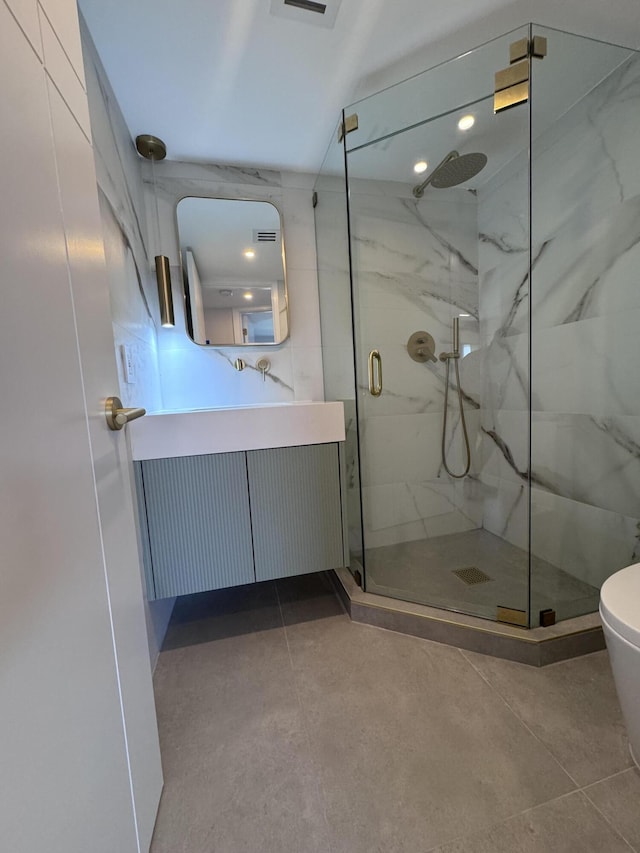 bathroom with a marble finish shower, vanity, and toilet