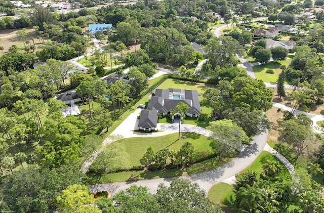 aerial overview of property's location with a tree filled landscape and nearby suburban area