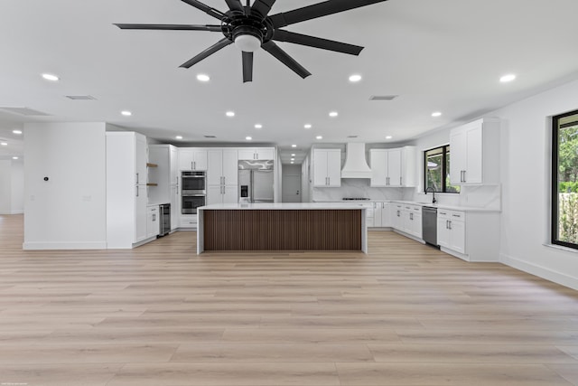 kitchen with stainless steel appliances, premium range hood, light wood-style flooring, baseboards, and recessed lighting
