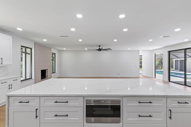 kitchen with stainless steel oven, open floor plan, recessed lighting, ceiling fan, and a large fireplace