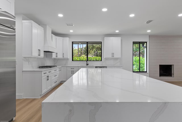kitchen with a spacious island, premium range hood, healthy amount of natural light, recessed lighting, and appliances with stainless steel finishes
