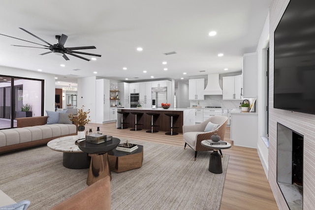 living room featuring light wood-style flooring, recessed lighting, ceiling fan, and a fireplace